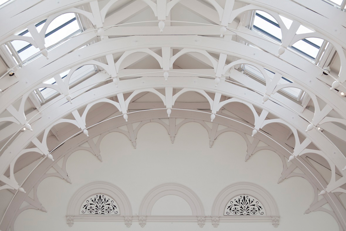 The restored vaulted ceiling of the upstairs gallery space. Its decorative trusses and iron works were hidden by a false ceiling for decades. Photography: Peter Heaton