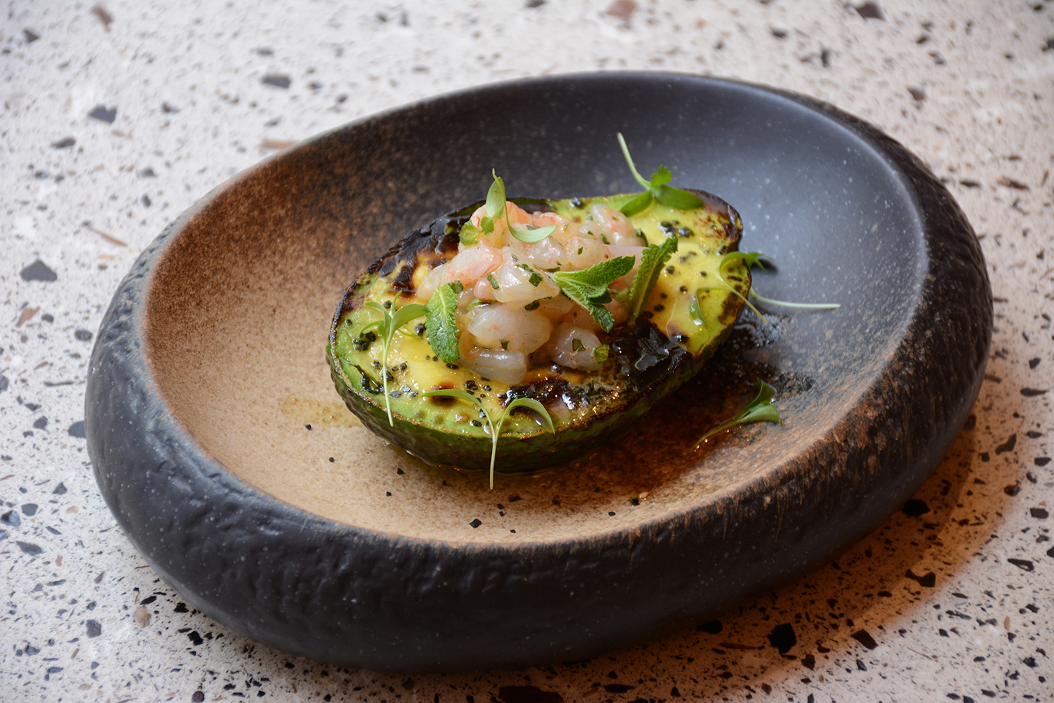 Grilled avocado topped by shrimp