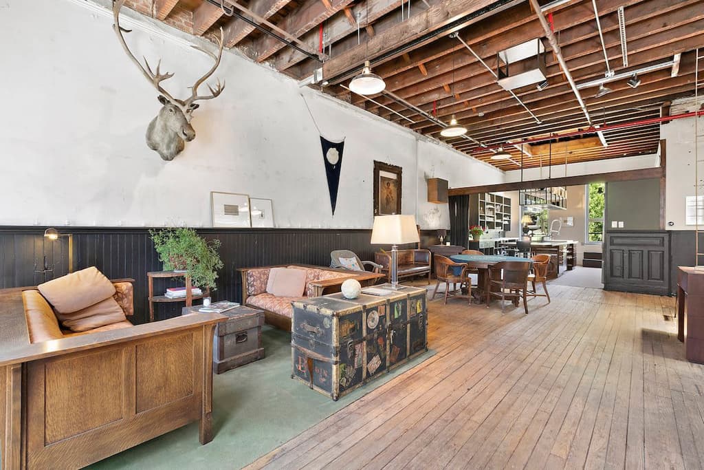 converted firehouse for sale in brooklyn's williamsburg: rustic meets industrial in the living room via exposed ceiling joists and wooden flooring