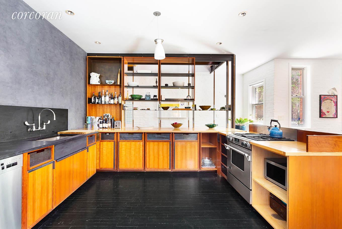 The Brooklyn carriage house has midcentury style teak cabinetry in the kitchen with modern stainless steel appliances.