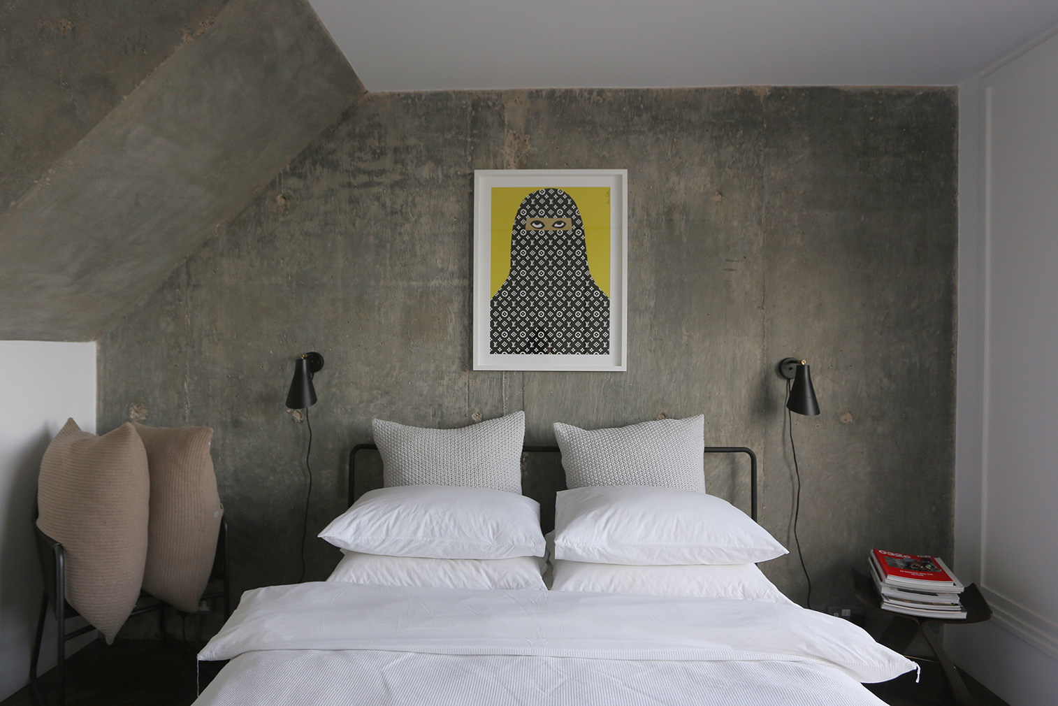 The master bedroom has exposed concrete walls and large picture windows