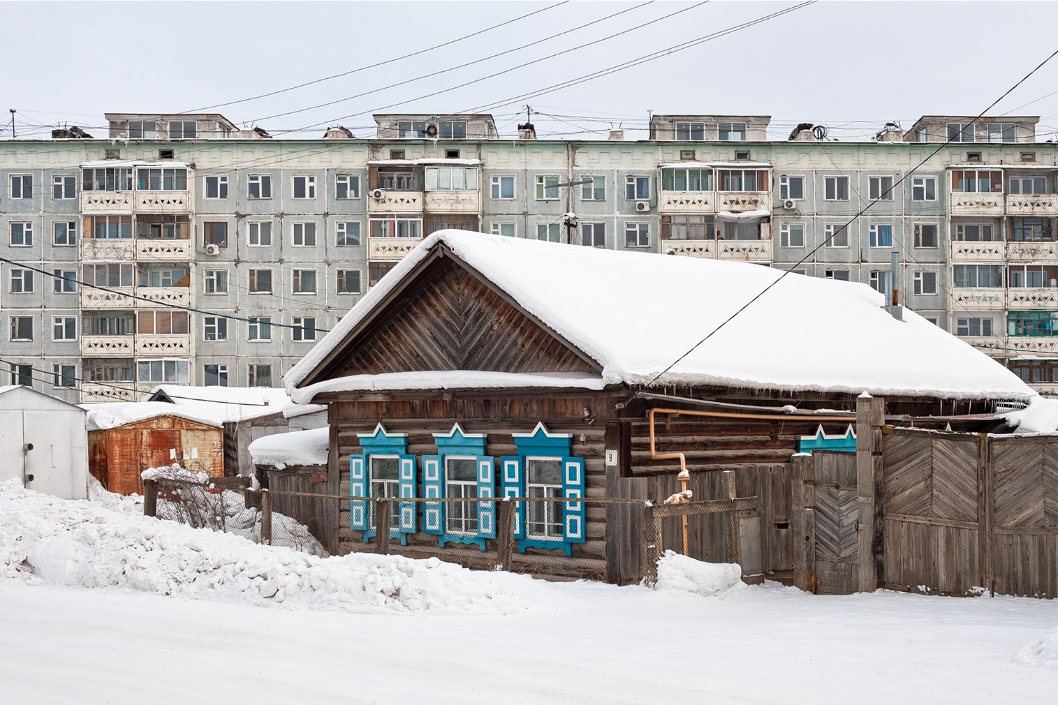 A typical Yakutian Izba and a prefab panel block from the late 1980s. Photography: Alexander Veryovkin © Zupagrafika, 2020