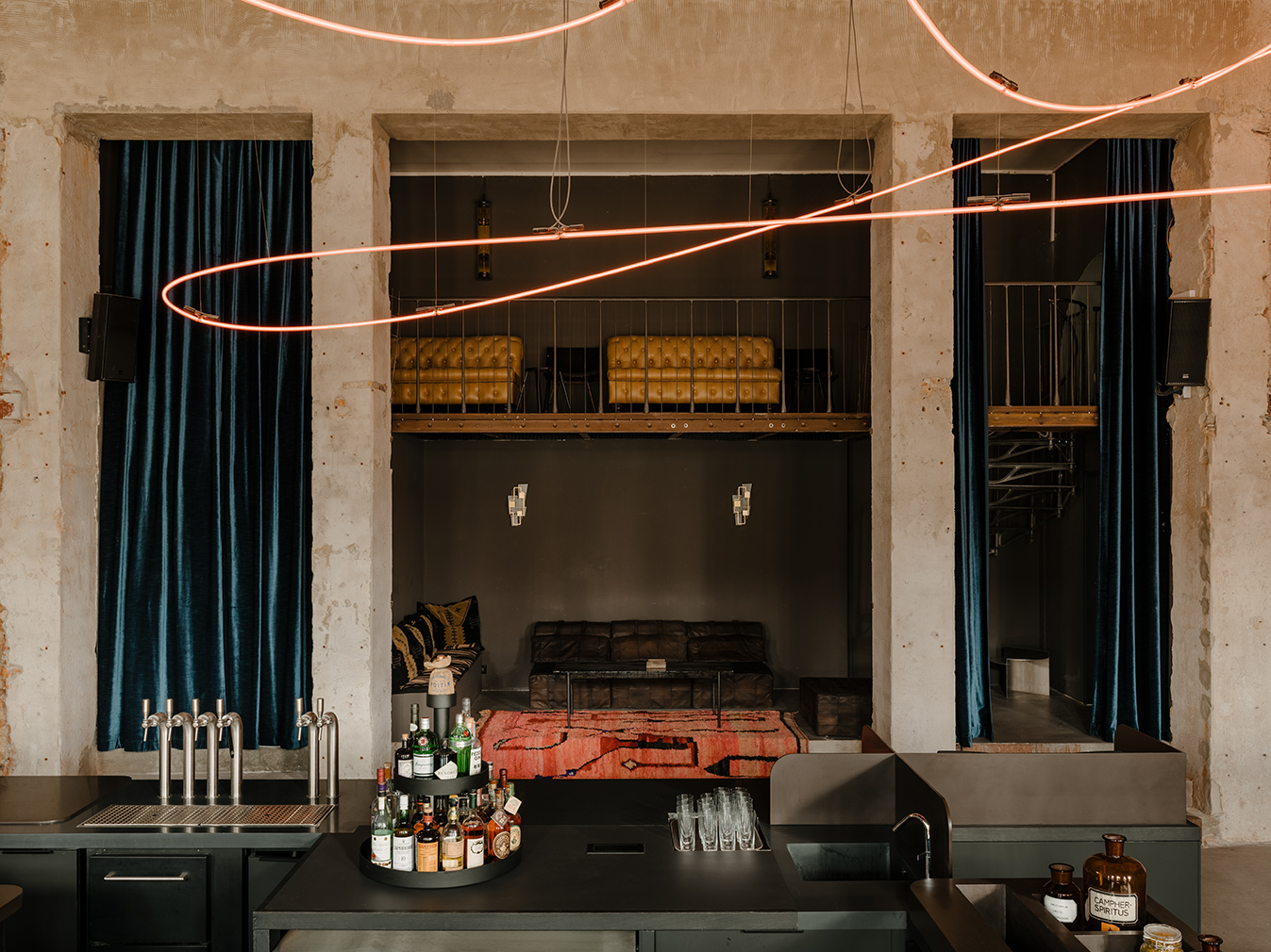 Kink bar in Berlin. The former brewery complex is now home to a moody and industrial inspired bar named Kink. Plaster and brick are contrasted by heavy velvet drapes, colourful floor cushions and a collection of art including a 100-ft-long neon rope installation by Kerim Seiler