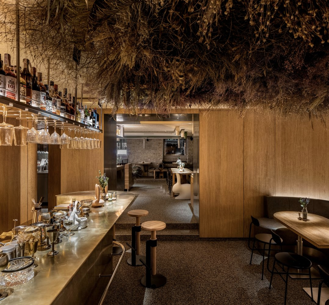 The second of the bar’s two main spaces features a striking art installation, made up of dried herbs, flowers and grasses that appear to be growing out of the ceiling overhead to haunting effect