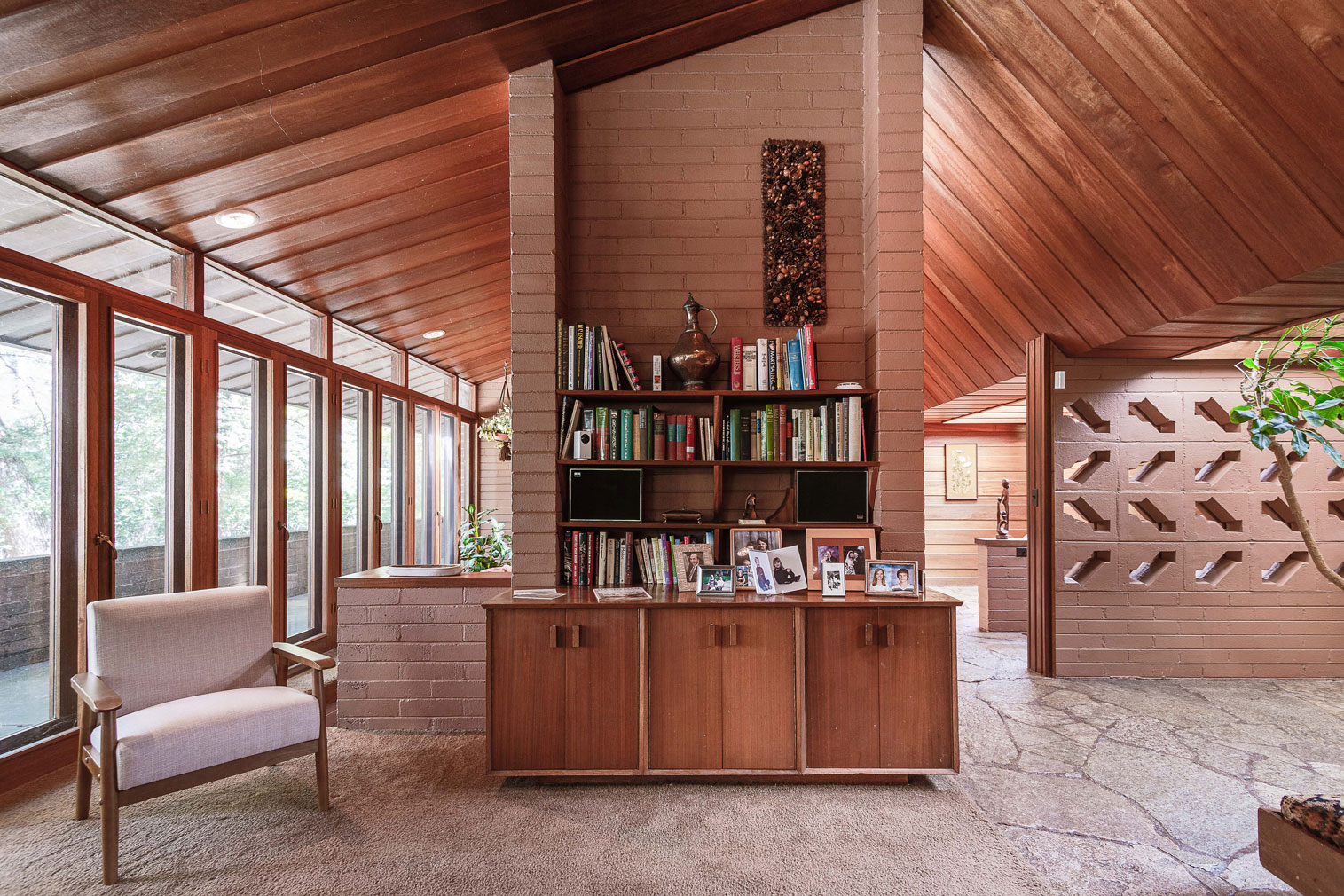 Brick walls have geometric cut outs and support sloping mahogany ceilings